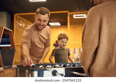 Playing table football game indoors. Family of dad, mother and son that are indoors. - Powered by Shutterstock