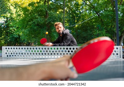 Playing table tennis outdoors on the open air sport ground.