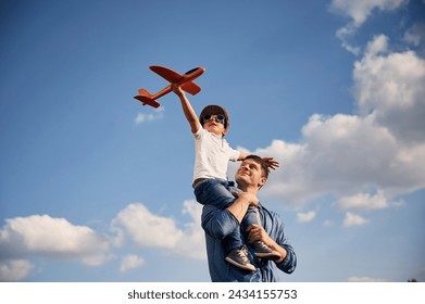 Playing with toy plane, sitting on the shoulders. Father and little son are having fun outdoors. - Powered by Shutterstock