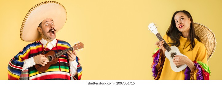 Playing ukulele. Half-size portraits of young couple, man and woman in mexican national clothing and sombrero over yellow background. Collage. Concept of human emotions, facial expression