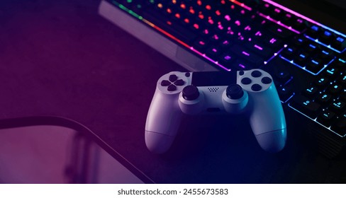 Playing video games. Computer keyboard with RGB lighting and wireless controller on table indoors - Powered by Shutterstock