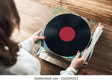 Playing vinyl records. Listening to music from vinyl record player. Retro and vintage music style. Woman holding analog LP record album. Stack of old records. Music collection. Music passion - Shutterstock ID 2162245311