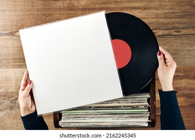 Playing vinyl records. Listening to music from vinyl record player. Retro and vintage music style. Woman holding analog LP record album. Stack of old records. Music collection. Music passion - Shutterstock ID 2162245345