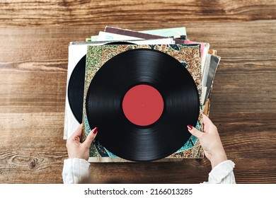 Playing vinyl records. Listening to music from vinyl record player. Retro and vintage music style. Woman holding analog LP record album. Stack of old records. Music collection. Music passion - Shutterstock ID 2166013285
