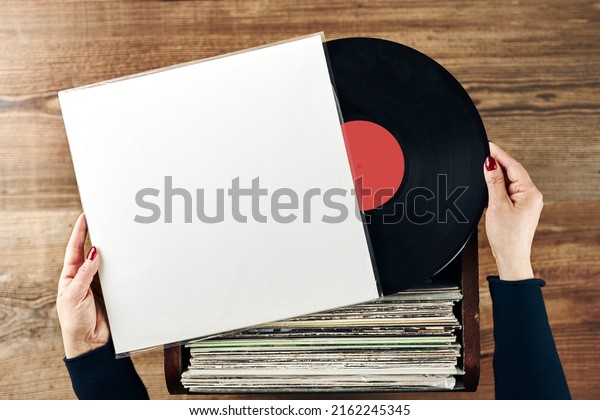 Playing vinyl records. Listening to music from\
vinyl record player. Retro and vintage music style. Woman holding\
analog LP record album. Stack of old records. Music collection.\
Music passion