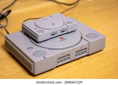 A Playstion Classic On Top Of An Original Playstation, A Comparison Of The Two, On A Wood Floor.