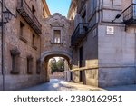 Plaza de la Villa passageway, stone medieval gate on Calle de Madrid (translation: Madrid Street) and Plaza de la Villa (Villa Square) intersection, narrow cobbled street in Madrid, Spain.