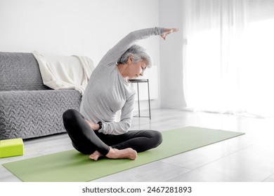 Pleasant 65-Year-Old Woman Does Exercises At Home On A Yoga Mat - Powered by Shutterstock