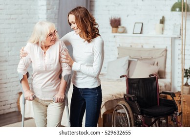Pleasant caring woman helping with rehabilitation her disabled grandmother