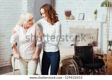 Pleasant caring woman helping with rehabilitation her disabled grandmother