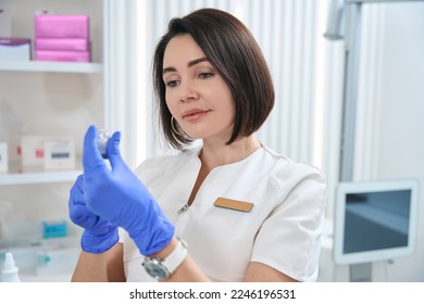 Pleasant clinic employee holds bottle of medicine in her hands - Shutterstock ID 2246196531