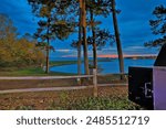 A pleasant evening at Lake Livingston State Park in Livingston, Texas, with a warm welcome sign at the entrance, surrounded by lush greenery and a glimpse of the lake in the background, inviting visit