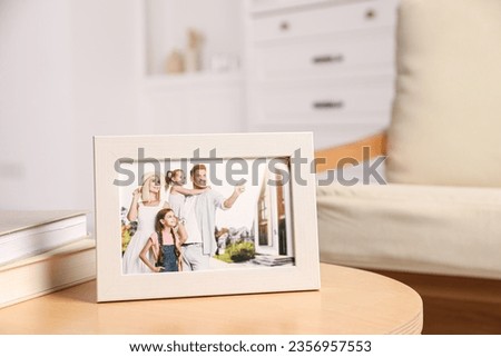 Pleasant memories. White photo frame with family portrait on wooden table indoors. Space for text
