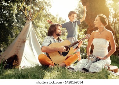 Pleasant Music. Nice Handsome Man Holding A Guitar While Playing Songs For His Family