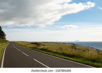 A pleasant road on the west coast of Scotland in Ayrshire on a sunny day with scenic view accross the Firth of Clyde to the island of the Ailsa 