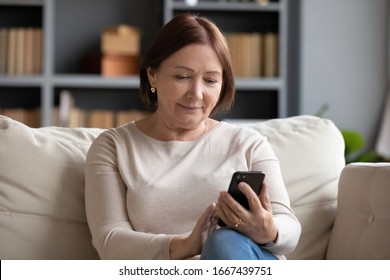 Pleasant senior older lady resting on couch, using applications on smartphone. Happy old mature woman chatting in messenger or social network with friends or children, shopping in internet store. - Shutterstock ID 1667439751