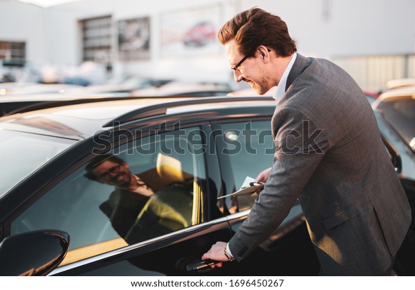 \
Pleasant smiling car salesman at work,\
buying a car, car\
dealership