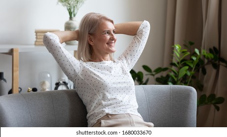 Pleasant smiling middle aged woman relaxing on cozy coach in modern living room, looking away. Happy older lady dreaming, visualizing future, resting, enjoying weekend free leisure time alone at home. - Shutterstock ID 1680033670