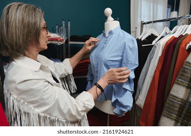 Pleasant Stylish Modern Elderly White-haired Caucasian Female Tailor Working On New Clothes In Fashion Clothing Design Atelier, Putting A Shirt From Her Luxury New Collection On A Tailoring Mannequin