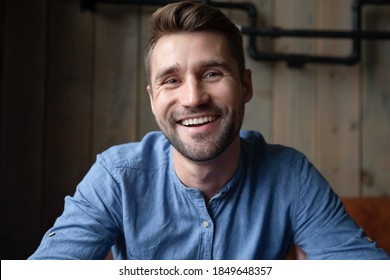 Pleasant Virtual Meeting. Headshot Portrait Of Smiling Millennial Man Spending Time At Internet Cafe Talking With Friends Online, Recording Vlog, Participating In Video Conference Looking At Camera