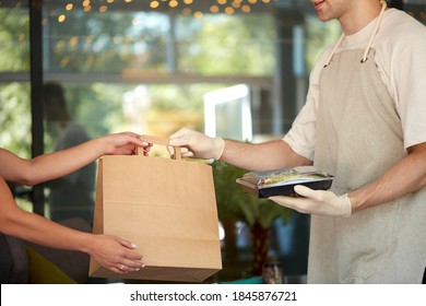 pleasant waiter man give orders in package to female customer, good service of restaurant staff. coronavirus, covid-19, epidemic outbreak, quarantine. waiter in protective gloves