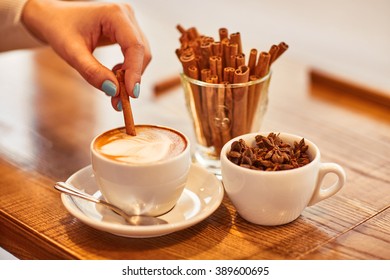 Pleasant woman putting cinnamon  into cup of coffee - Powered by Shutterstock