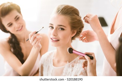 Pleasant young bridesmaids helping the bride to get ready - Powered by Shutterstock