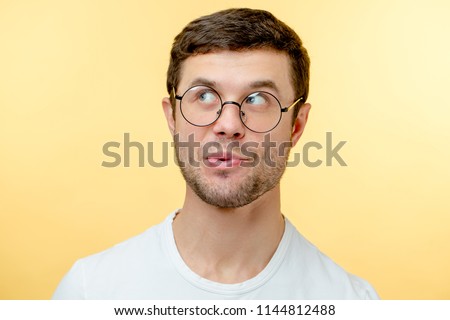 pleasant young man in glasses whistling a song. guy with interesting expression. look up. indifference concept