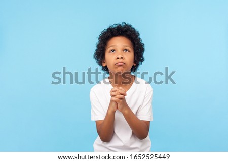 Please, I'm begging. Portrait of upset little boy praying to god with hands held together, apologizing for bad behavior, looking up with imploring eyes. indoor studio shot isolated on blue background Foto stock © 