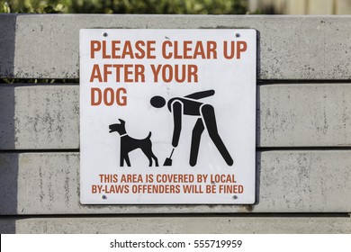 Please Clear Up After Your Dog. A Written Sign With An Image Of A Responsible Pet Owner Cleaning Up After Their Dog.