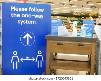 'Please follow the one way system' sign in grocery store in the UK next to disinfectant for trolleys illustrating concept of safety precautions in Uk during the coronavirus pandemic