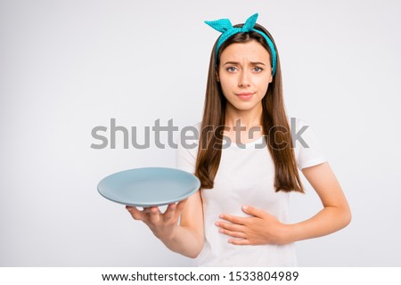 Please give me more food! Portrait of negative unhappy girl follow unhealthy diet starving hold  plate feel stomach ache wear style clothes isolated over white color background