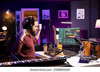 Please happy songwriter creating new music on daw software, using headset to listen to the final product in home studio. Young music producer editing audio files recordings on pc. - Powered by Shutterstock