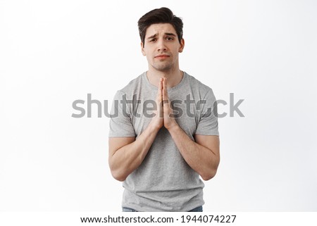 Please help. Coy man begging for favour, need something, pleading you with desperate gloomy face, standing over white background