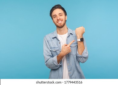 Please, hurry up! Portrait of cheerful punctual man in worker denim shirt pointing at wrist watch and smiling, showing smartwatch devise with mock up display. indoor isolated on blue background - Powered by Shutterstock