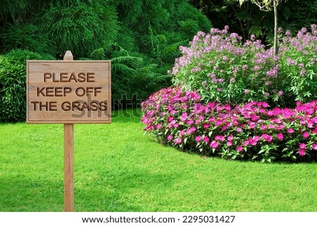 Please Keep Off The Grass - concept with wooden pole on a green meadow with sign indicating 