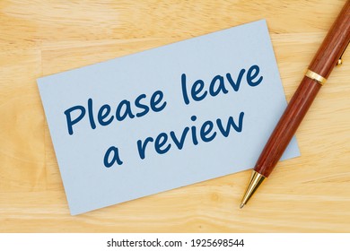 Please Leave A Review Message On Blue Paper Index Card With Pen On Wood Desk