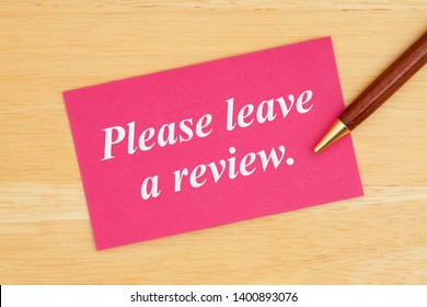 Please Leave A Review Text On Pink Card With Pen On Wood Desk