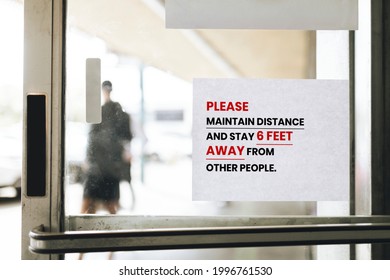 Please Maintain Distance And Stay 6 Feet Away From Other People Paper Sign On A Glass Door