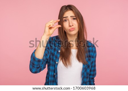 Please, some more. Portrait of cute girl in checkered shirt showing small size or little bit gesture with fingers, looking with imploring grimace. indoor studio shot isolated on pink background Foto stock © 