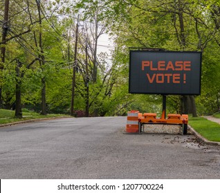 Please Vote Electric LED Sign On Trailer On A Suburban Street Lined With Trees