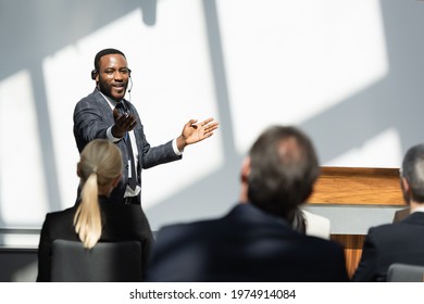 Pleased African American Lecturer Pointing With Hand During Seminar With Business People