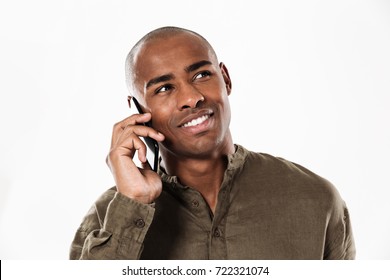 Pleased African Man Talking By The Smartphone And Looking Away Over White Background