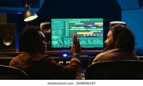 Pleased artist and tracking engineer doing high five gesture after creating a song together, happy with the final result. Team of singer and producer celebrating successful track collab. Camera A.