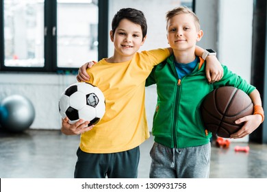 Pleased boys embracing while posing with balls - Powered by Shutterstock