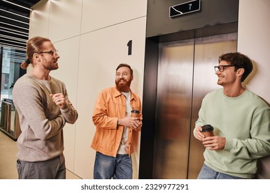 pleased business colleagues in stylish casual clothes holding takeaway drinks in papers cups while waiting for elevator, successful entrepreneurs talking during coffee break in modern office - Powered by Shutterstock