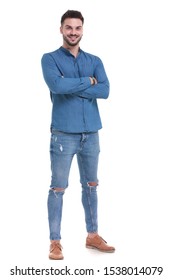 Pleased Casual Man Standing With His Arms Crossed At His Chest While Wearing Blue Jeans And Suit On White Studio Background