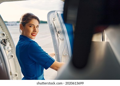 Pleased Dark-haired Lovely Stewardess Opening The Airplane Door