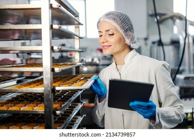 Pleased Female Food Plant Supervisor With Tablet Checking On Cookies Quality.