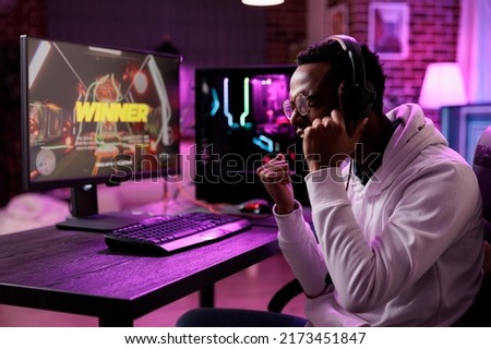 Pleased gamer celebrating video games championship win, streaming online gaming tournament. Cheerful adult winning action rpg gameplay competition on computer, having fun on stream.